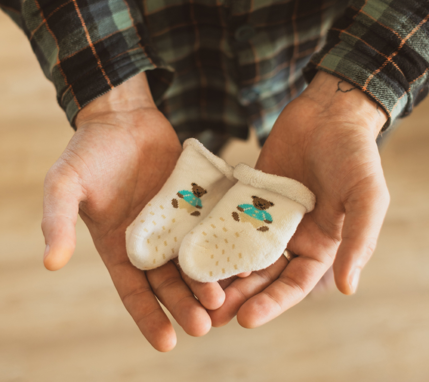 A man holding a pair of baby socks